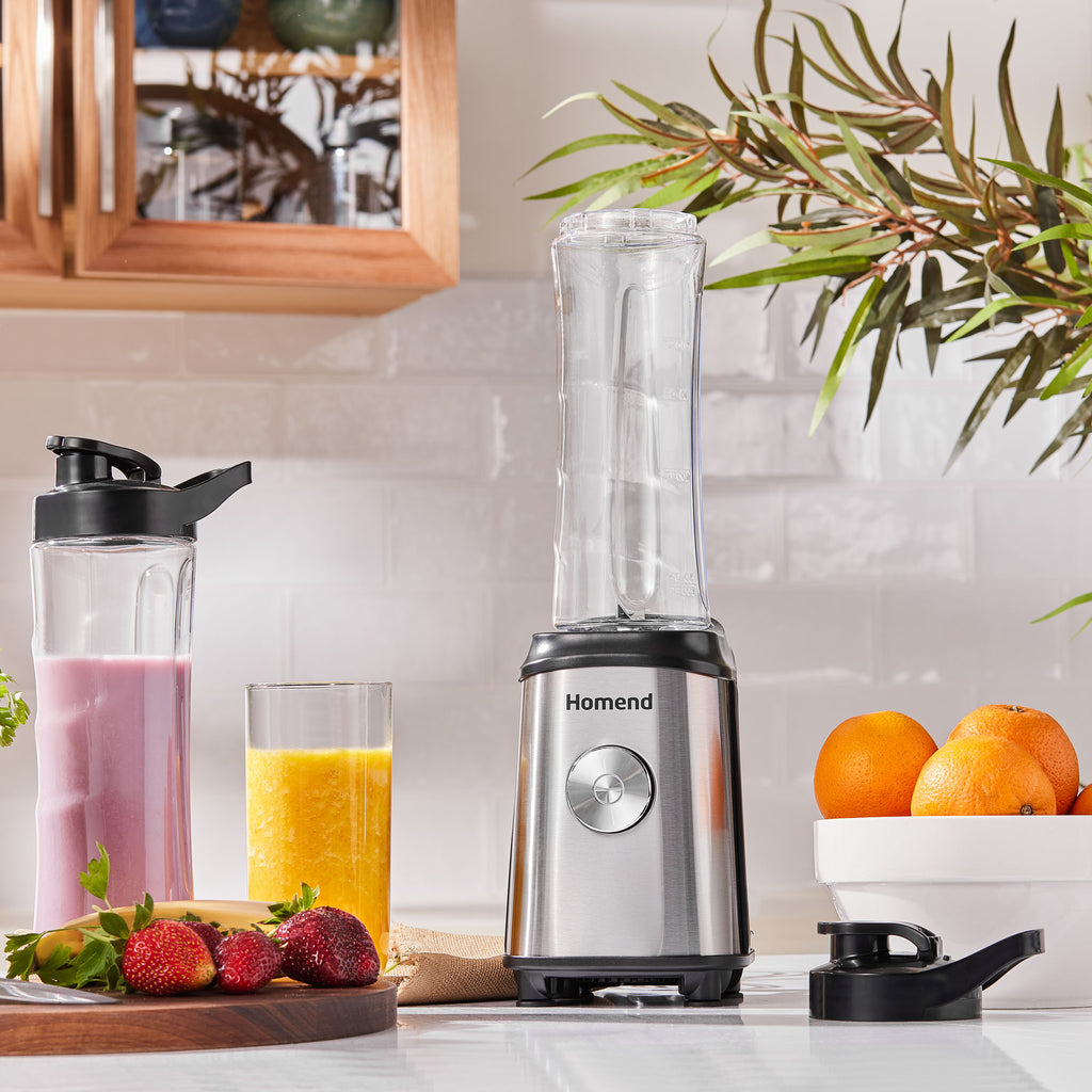 A modern blender on a kitchen counter with fruit and smoothies. 2 bottles and 2 covers for the bottles. bPA free healthy bottles with stainless steel body of powerful blender.