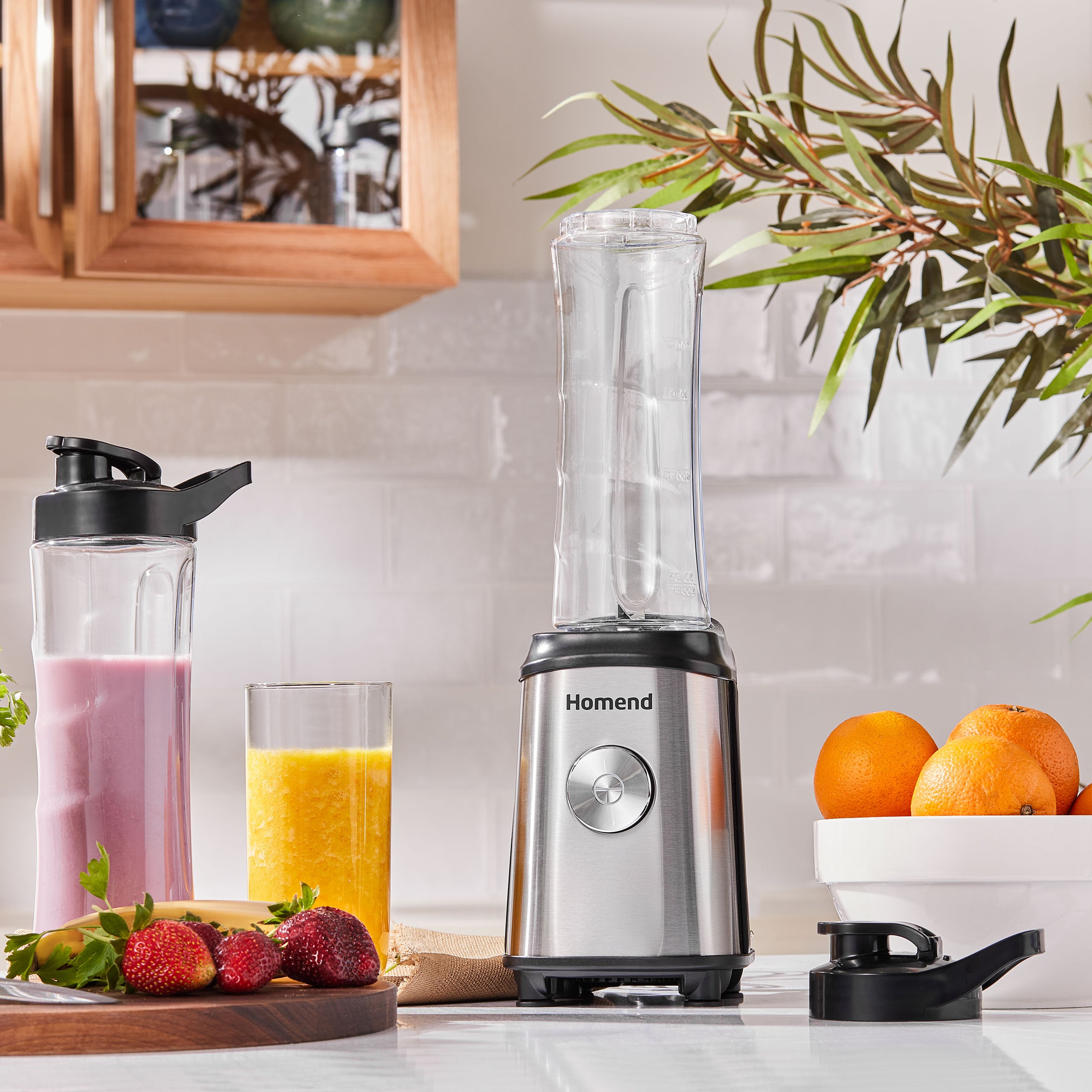 A modern blender on a kitchen counter with fruit and smoothies. 2 bottles and 2 covers for the bottles. bPA free healthy bottles with stainless steel body of powerful blender.